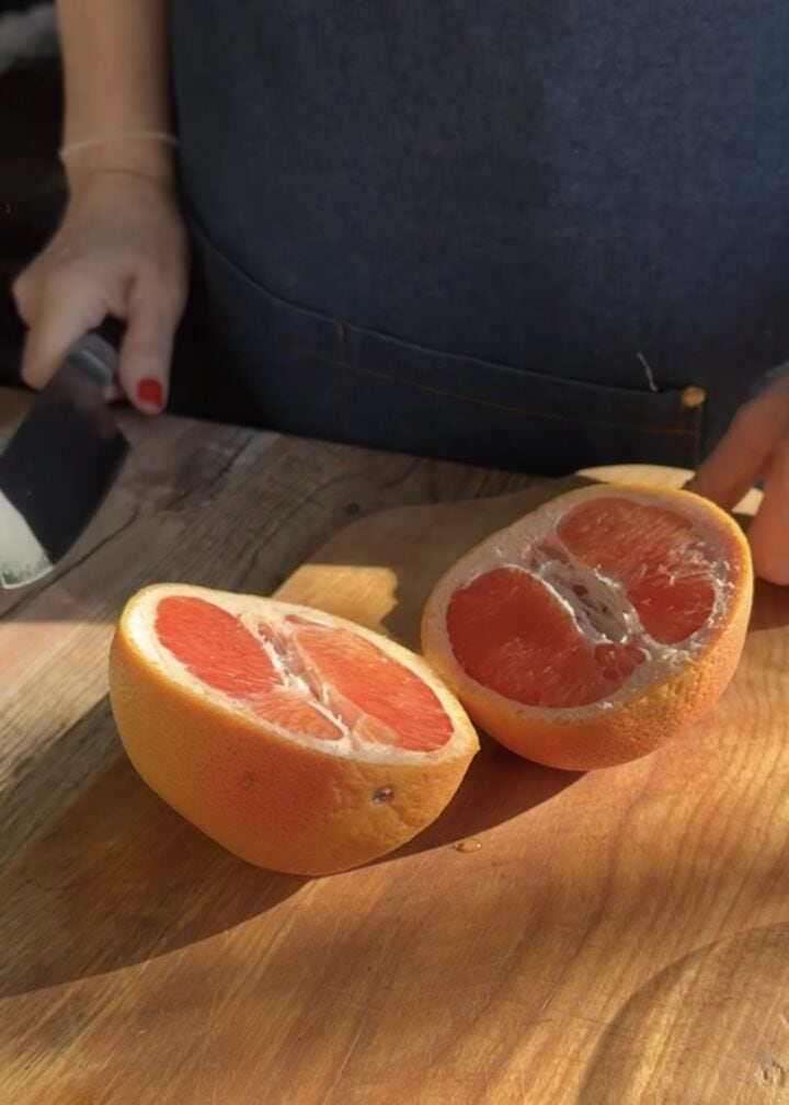 grapefruit sliced in half on wood cutting board 
