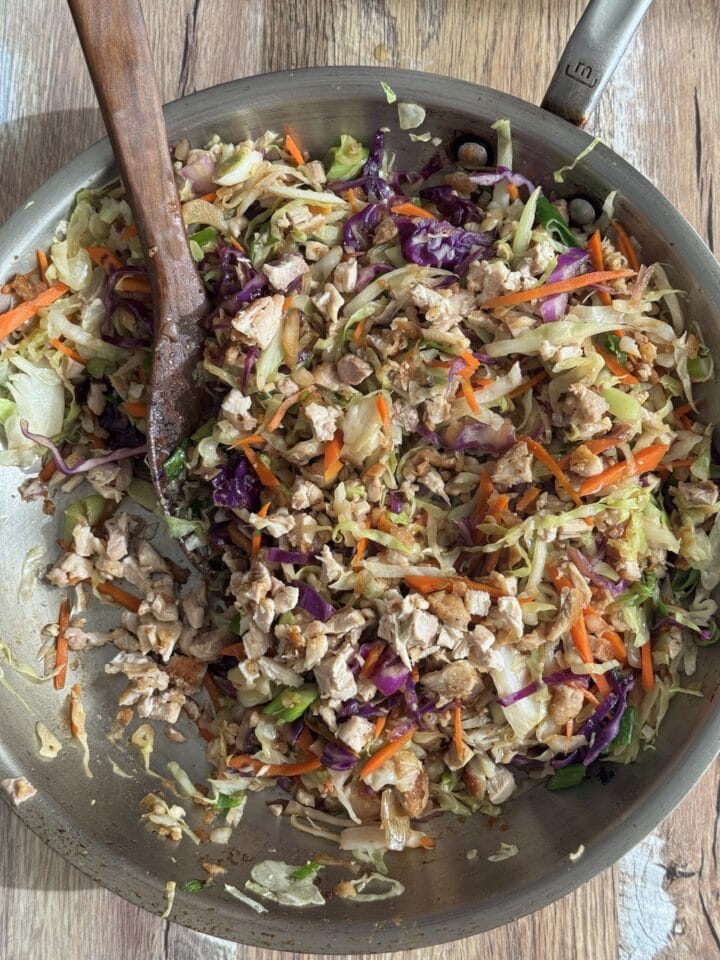 egg roll in a bowl recipe in a pan with a wooden spatula in it