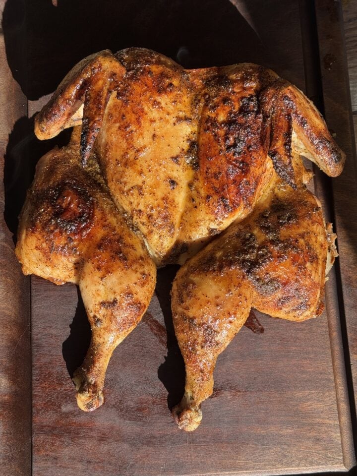 roasted spatchcock chicken resting on wood board
