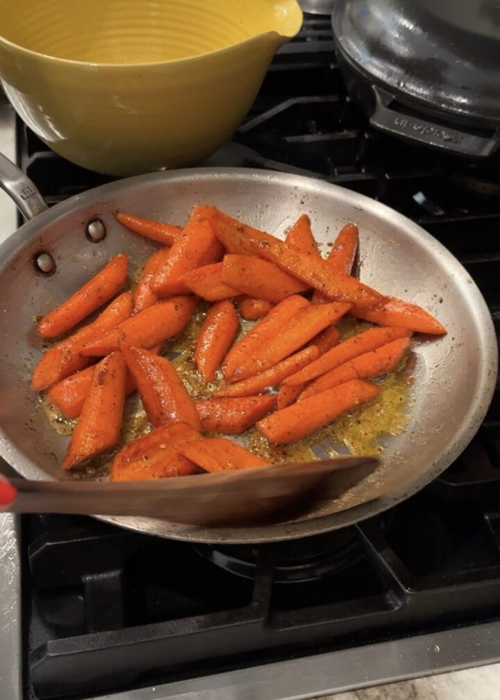 spiced carrots sautéing in stainless steel pan 