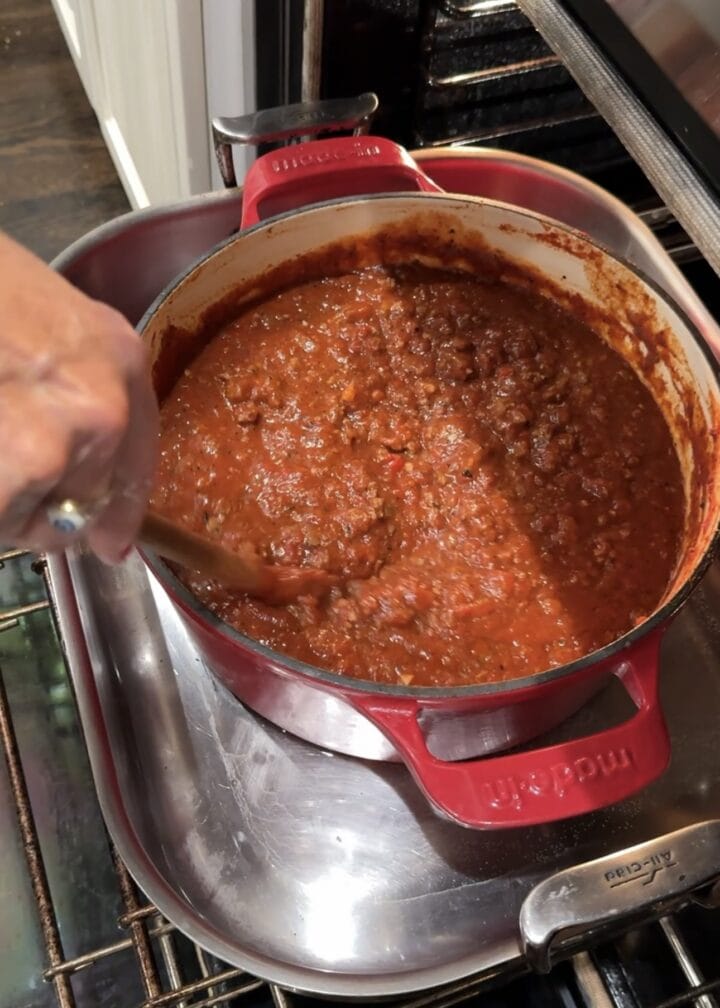 teri stirring sloppy joe in a red dutch oven resting on an oven rack