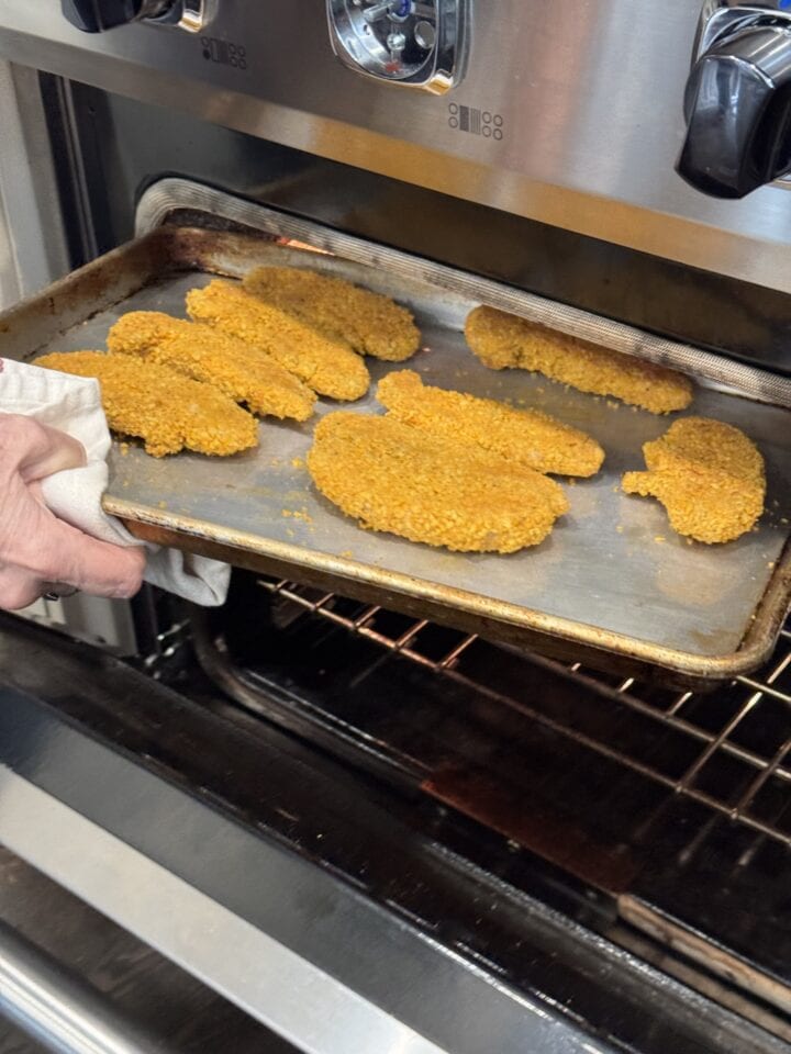 chicken fingers on a sheet tray going in the oven