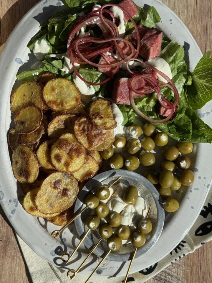 dirty martini dip on a salad with potato wedges, olives, lettuce and onions