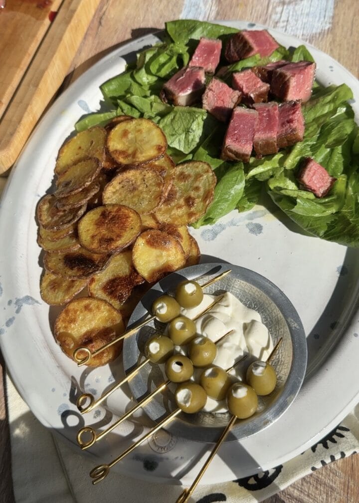 dirty martini dip in a bowl with olives on a platter with salad