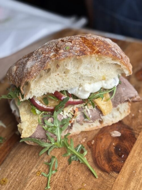 a roast beef sandwich with dirty martini dip on a cutting board