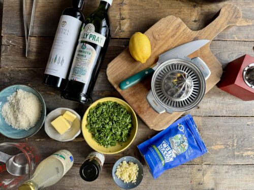 ingredients for clam pasta laid out on a wooden surface
