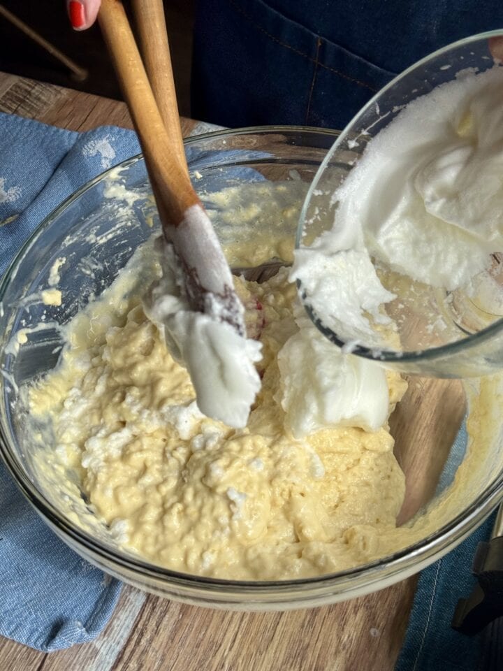 egg whites being added to the blueberry waffle batter with a spatula
