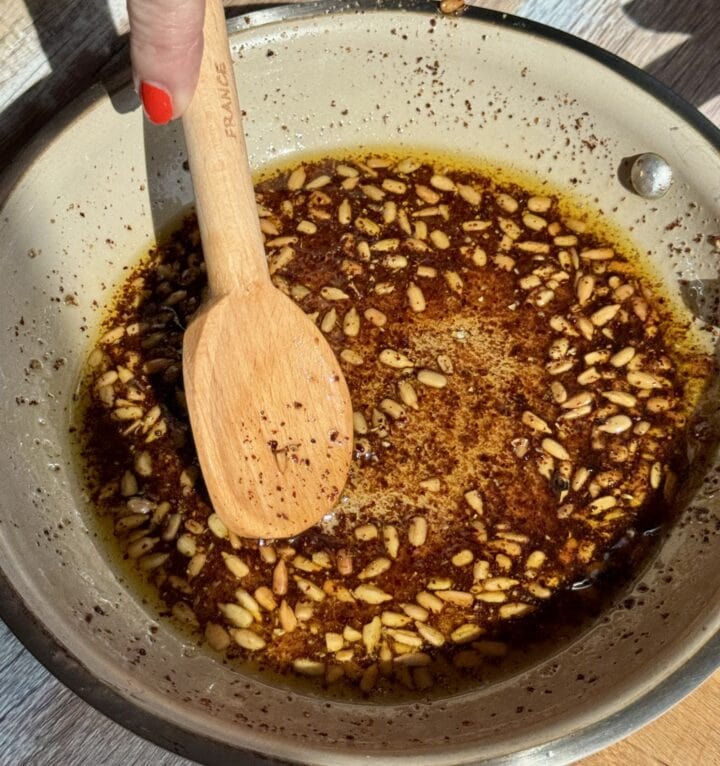 sunflower seeds in a saute pan with a wooden spoon in it