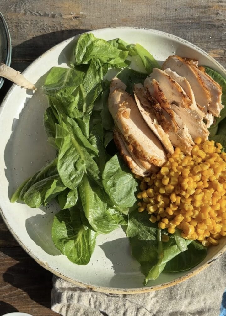greens, corn and chicken on a white platter