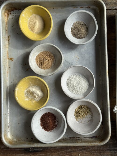 spices for chicken in small bowls on a sheet pan