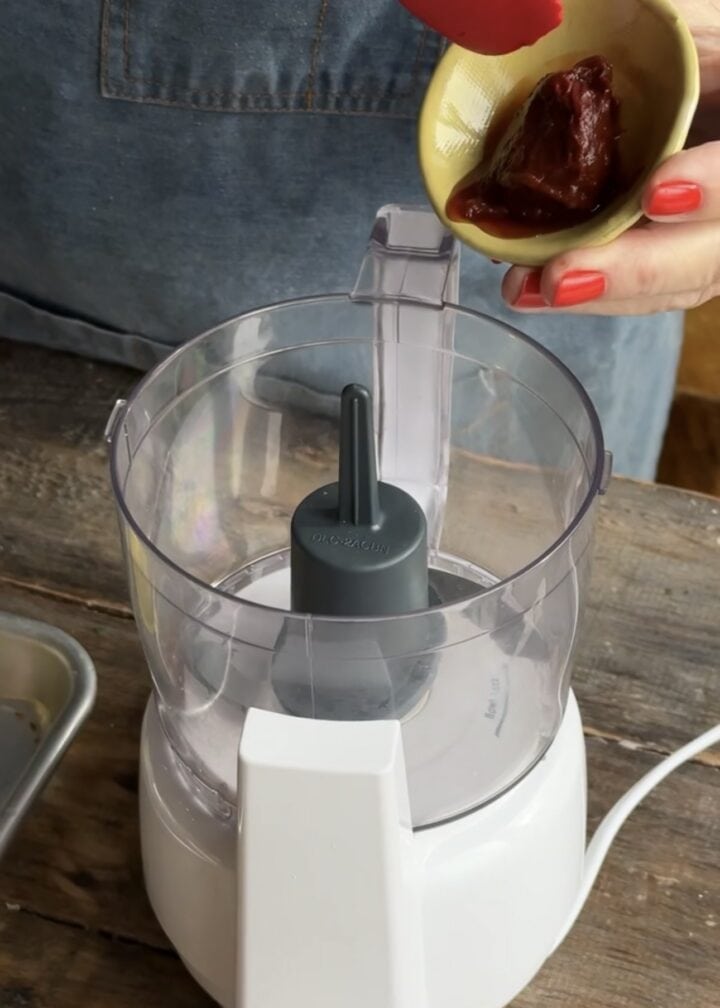 teri adding chipotle peppers to a food processor