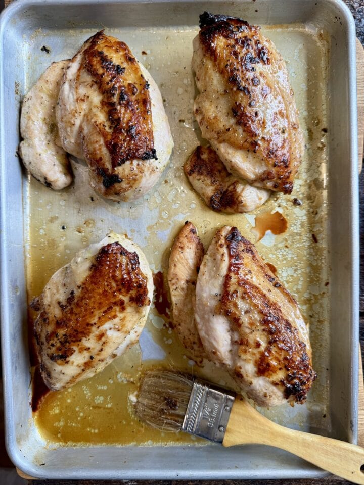 four roasted chicken breasts on a sheet pan