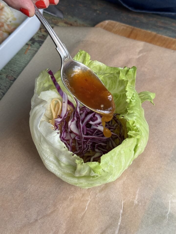 sweet and sour sauce pouring into a lettuce wrap