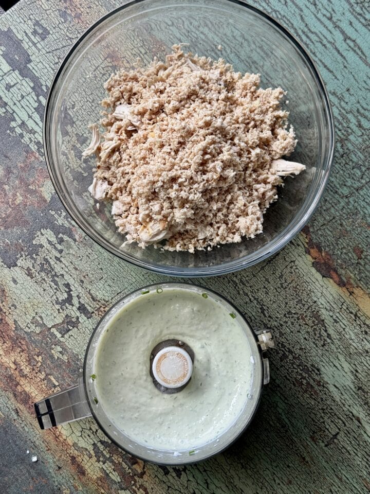 blitzed chicken in a glass bowl with dressing in a food processor next to it