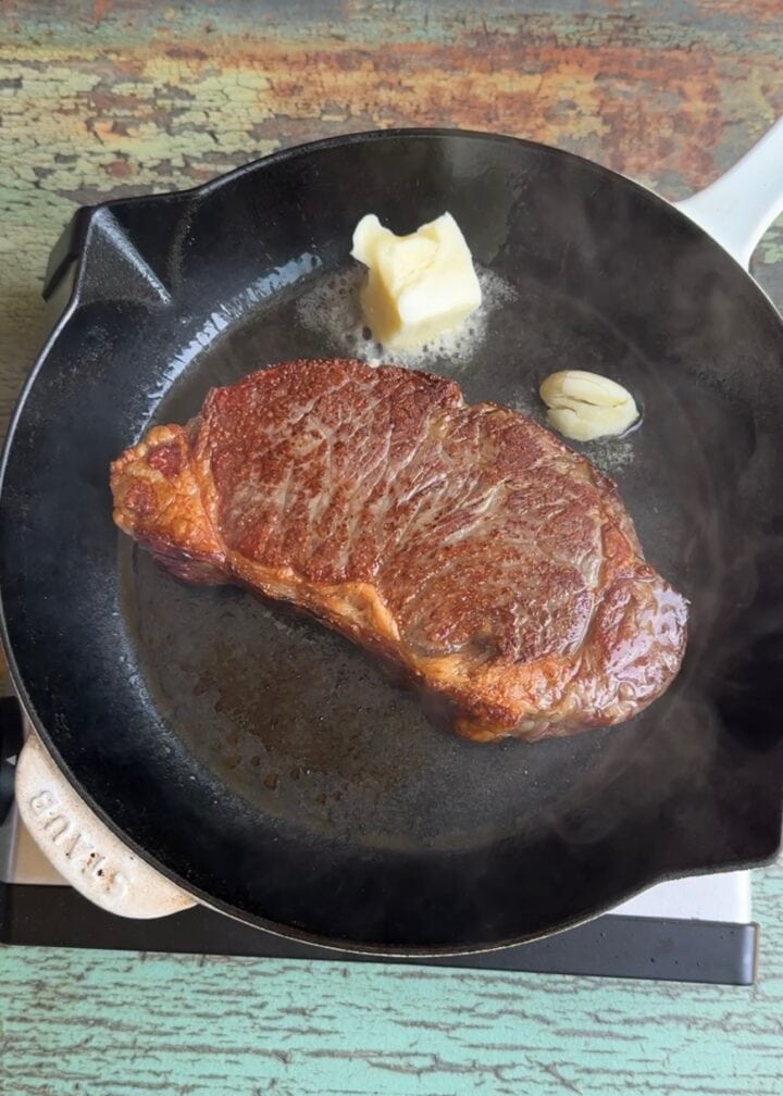 steak in a cast iron pan with butter and garlic