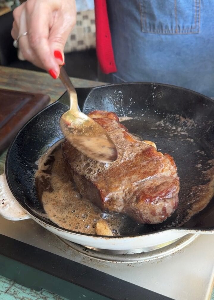 butter basting a steak in a cast iron skillet