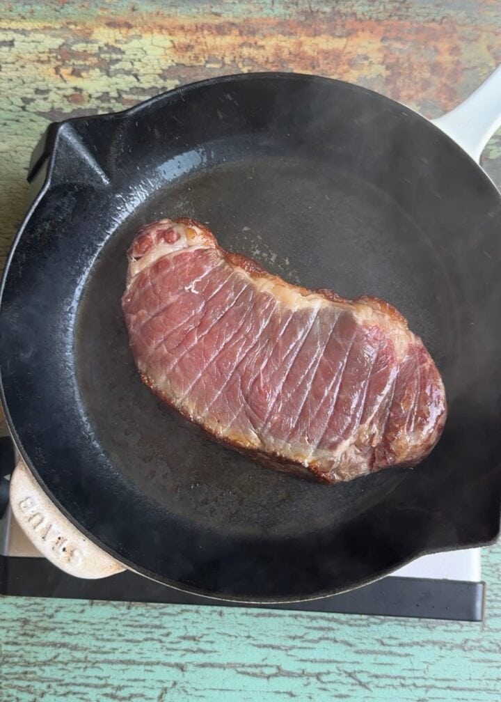 steak searing in a cast iron pan