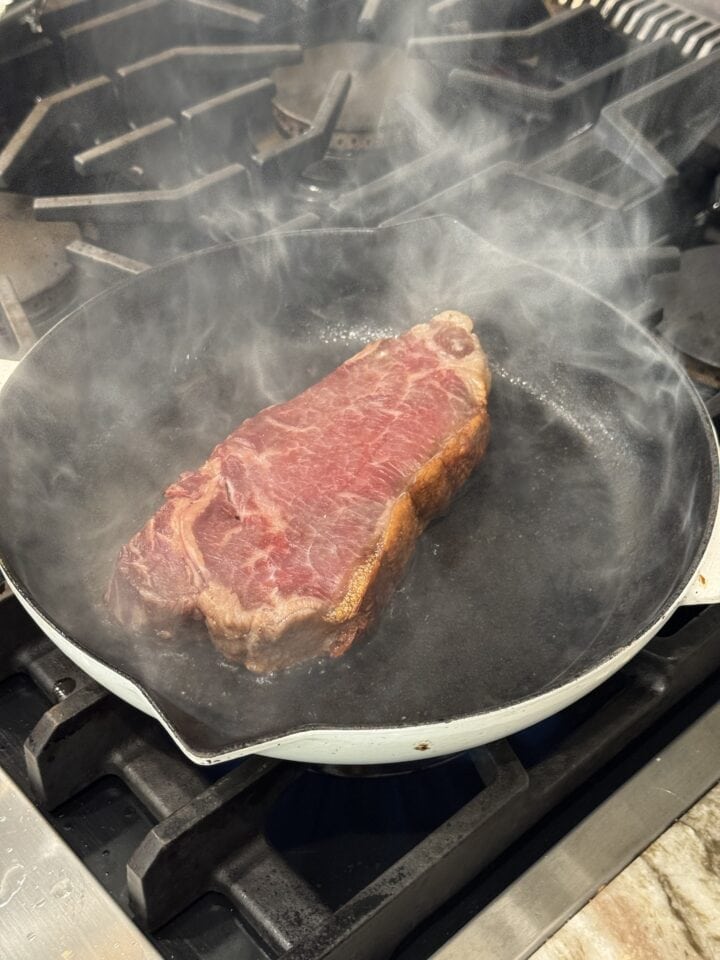 steak searing in a cast iron pan