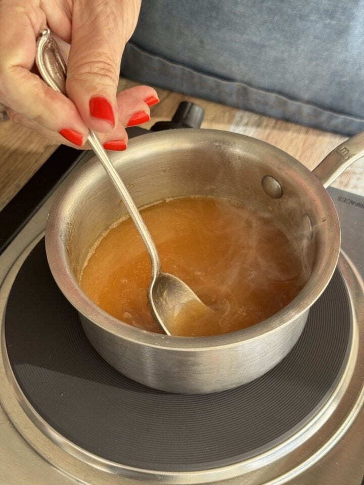 sweet and sour sauce in a pan with a spoon in it
