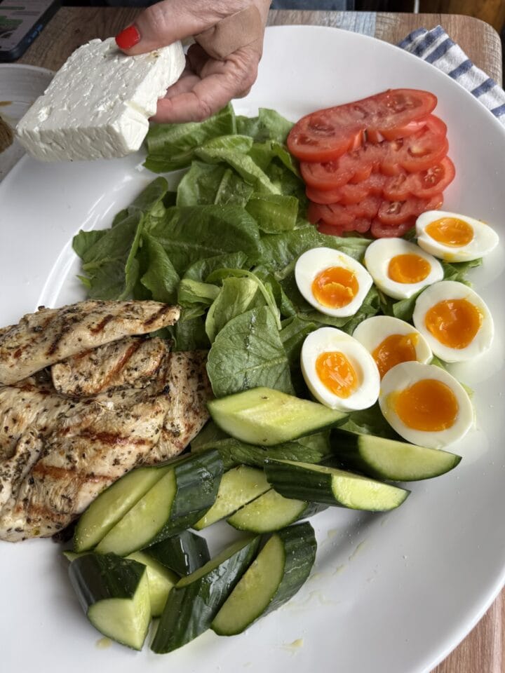 lettuce, tomatoes, chicken, and jammy eggs on a white platter