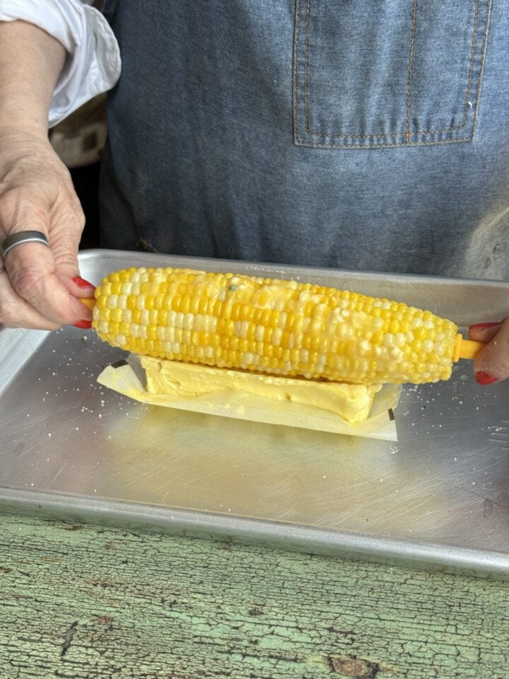 corn rolling in a stick of butter that is slightly melted