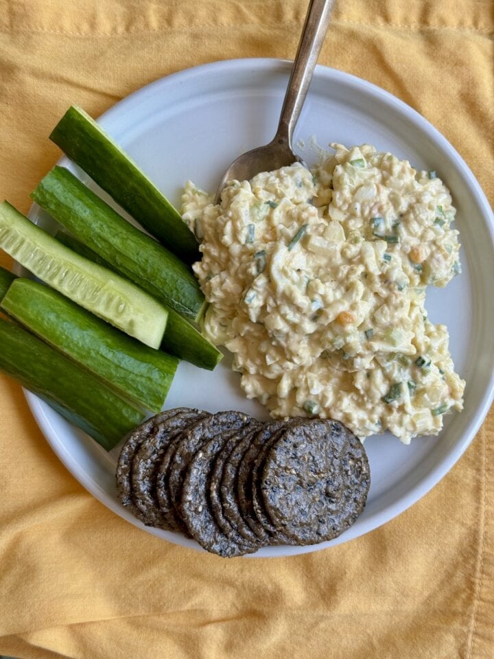 egg salad on a plate with cucumbers and crackers