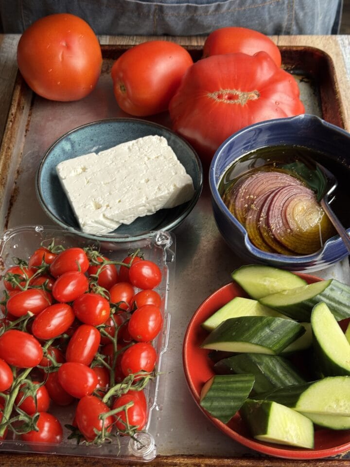 vegetables and feta cheese in small bowls on a baking sheet