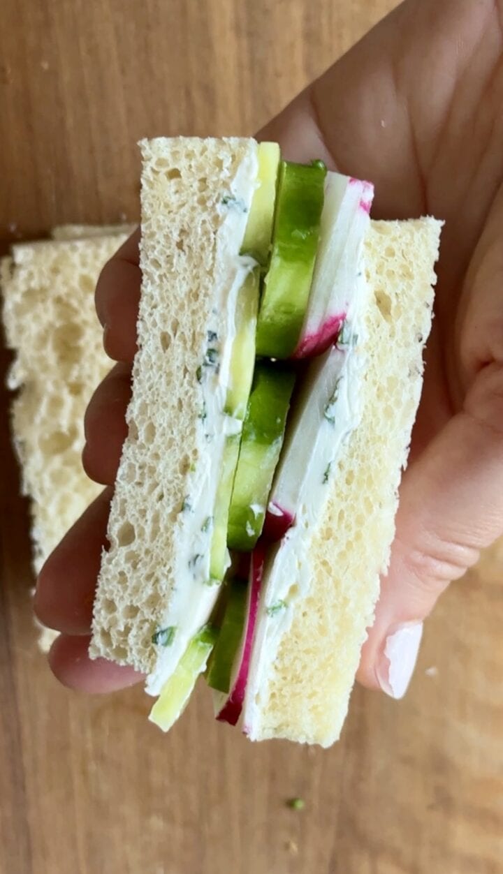 a cucumber sandwich being held in a hand