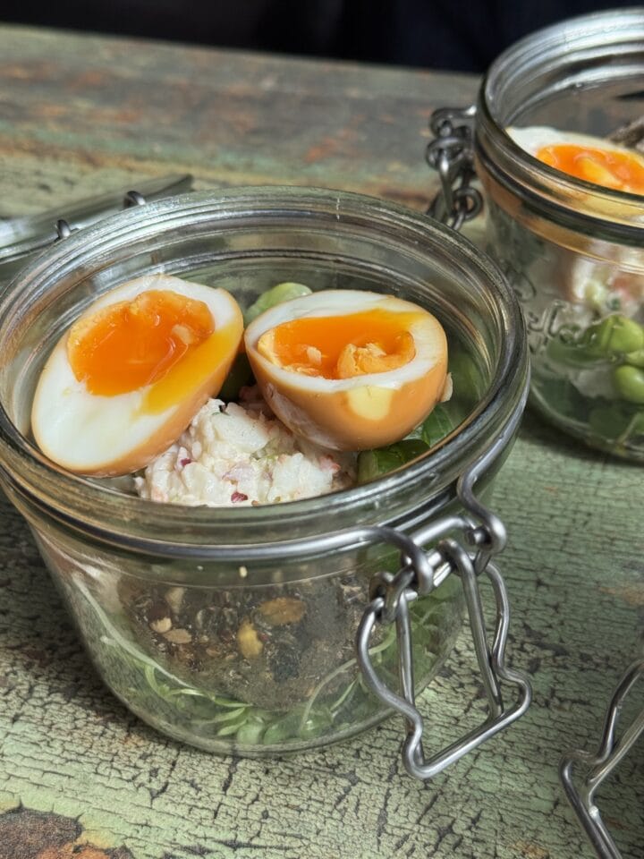 soy marinated eggs in a shrimp salad in a small glass jar
