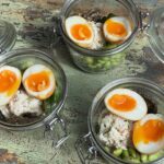three small jars filled with poached shrimp salad and topped with 2 egg halves