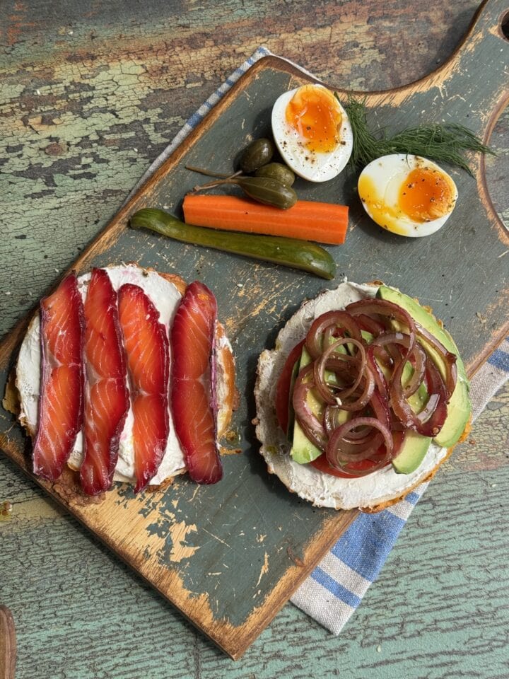 salt cured salmon on two bagel halves with jammy eggs on the side