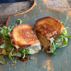 sliced apple grilled cheese on a blue wooden cutting board