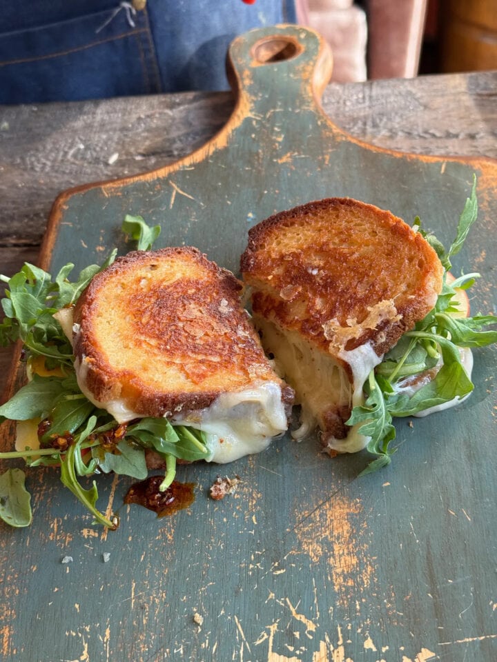 sliced apple grilled cheese on a blue wooden cutting board