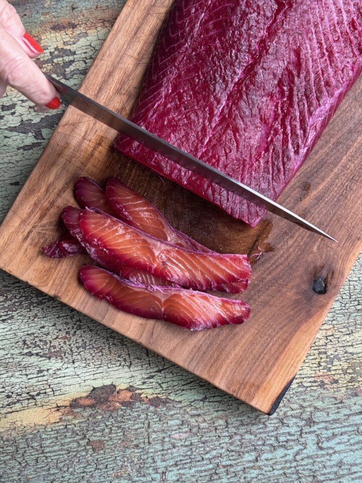 teri slicing salt cured salmon on a wooden cutting board