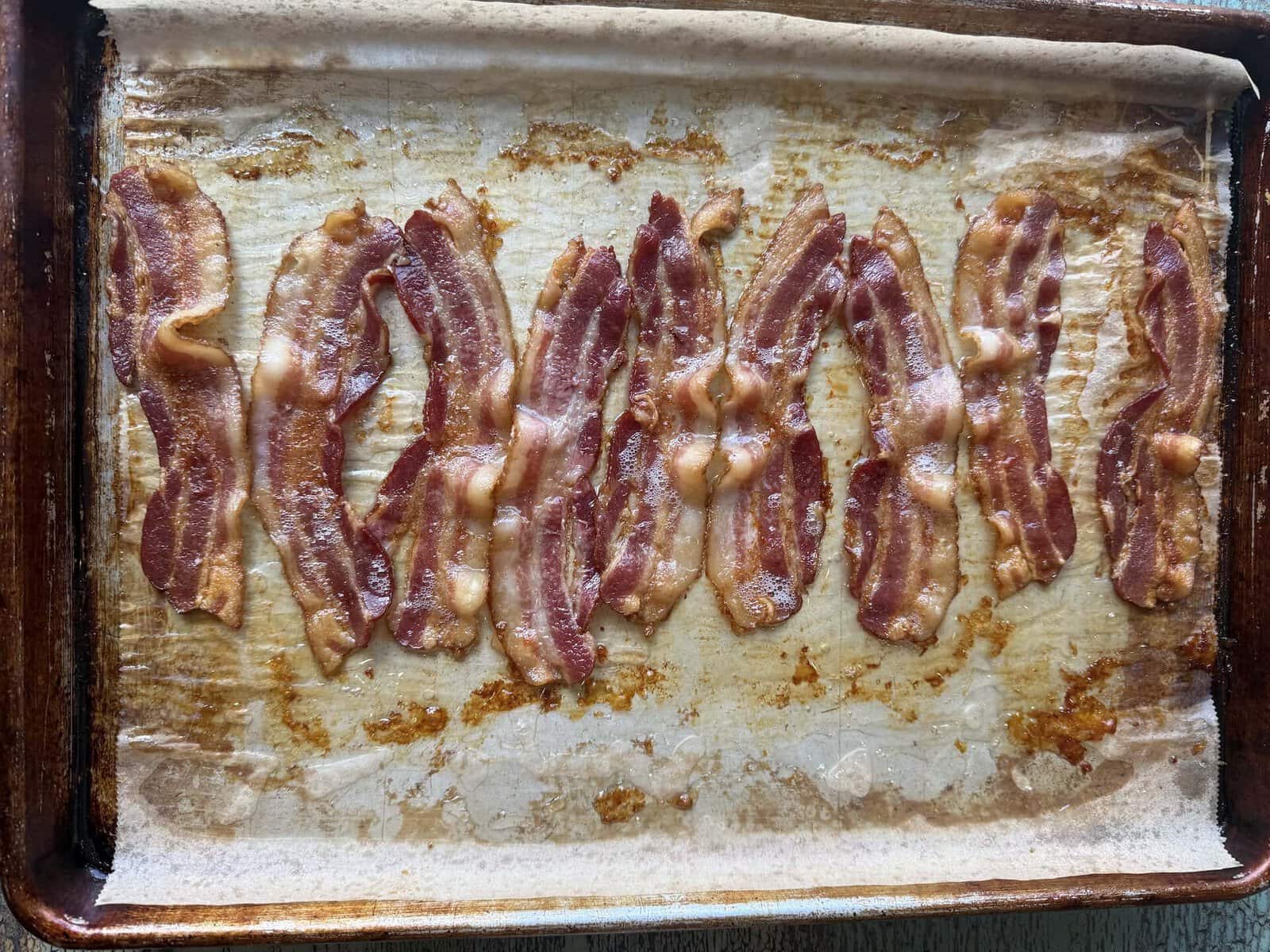 thick cut bacon cooked on a sheet pan with parchment paper