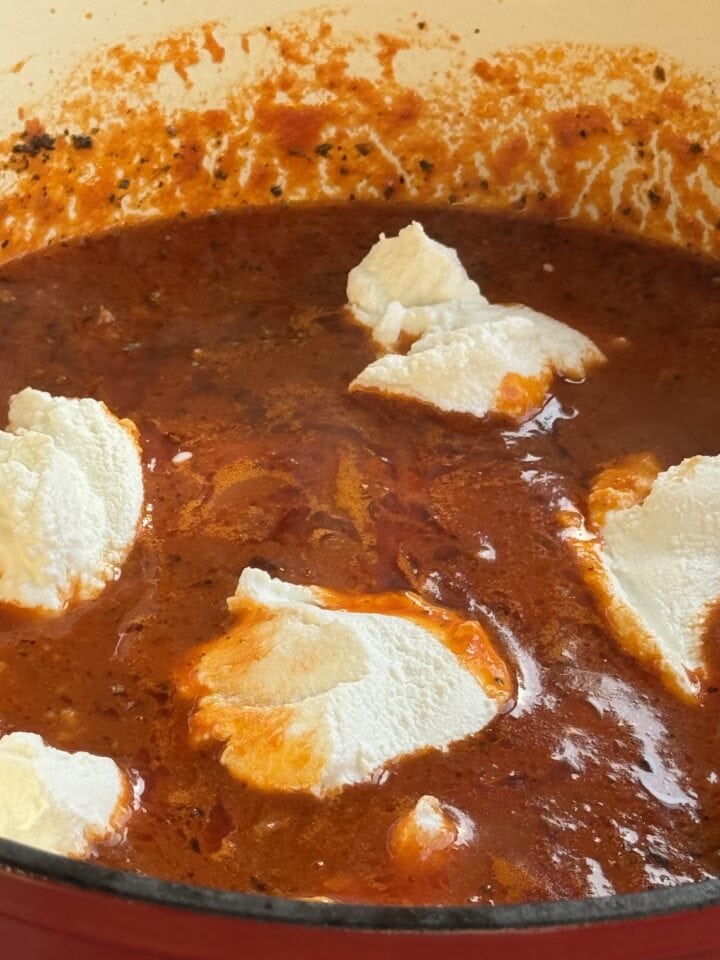 ricotta dollops on top of a lasagna in a dutch oven
