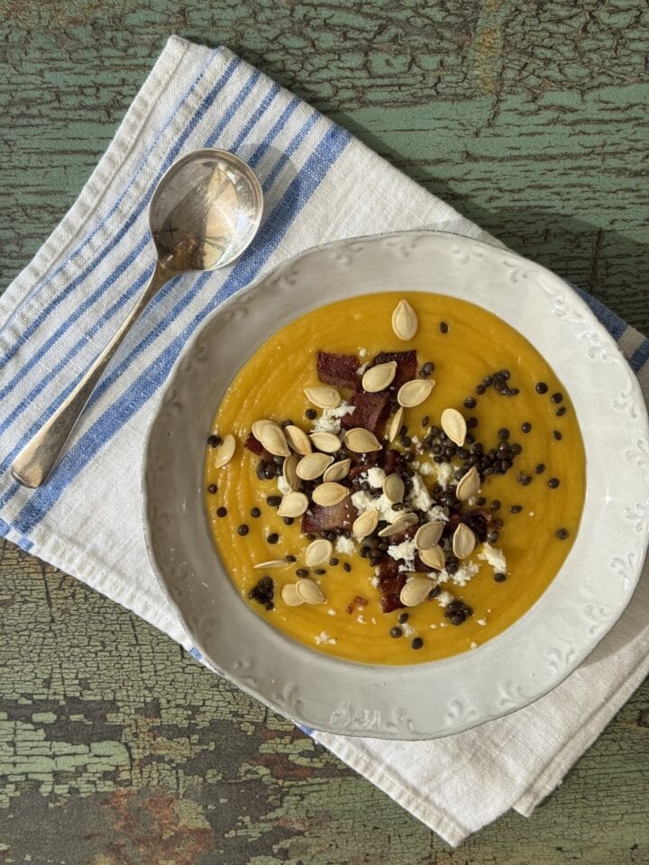 pumpkin soup in a white bowl with a spoon next to it