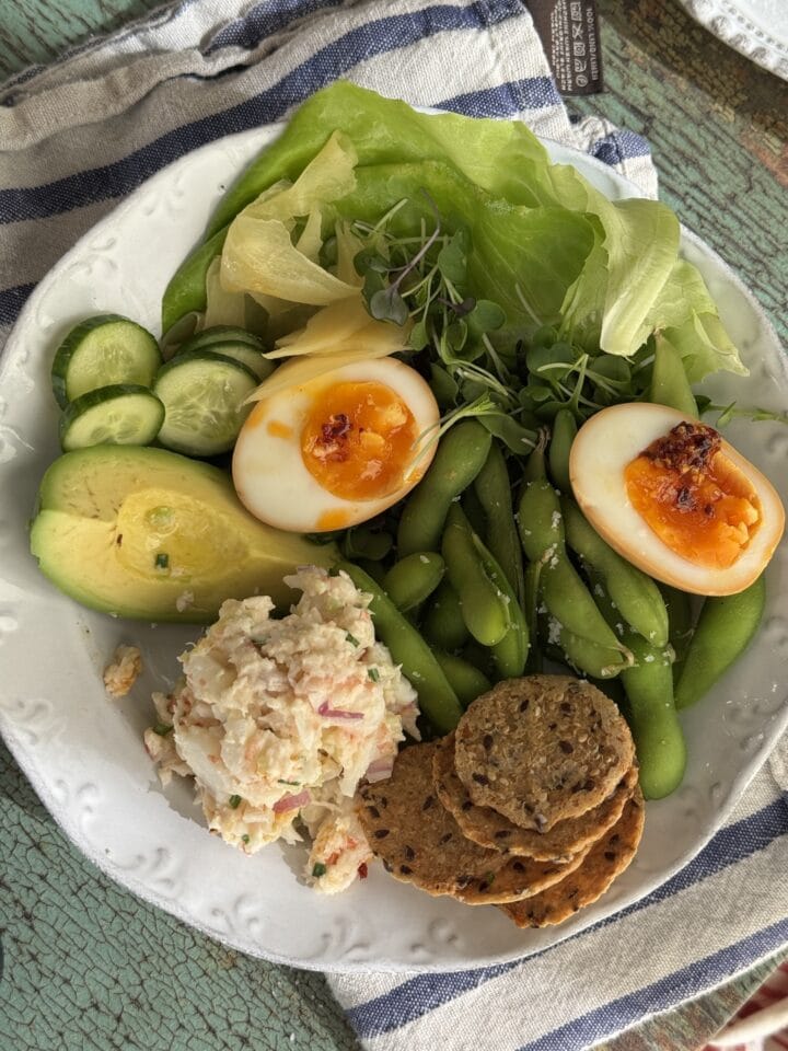 soy marinated eggs on a white plate with lettuce and avocado and shrimp